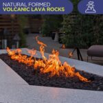 A lit gas fire pit with lava rock in an outdoor living space