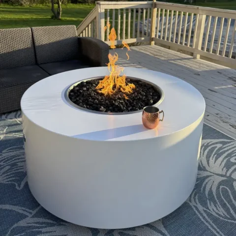 The Unity Powder Coated Metal Fire Pit 24 Inches High in White in a backyard setting