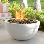 GFRC Concrete Luna Fire Bowl in White Limestone on the patio in a backyard.