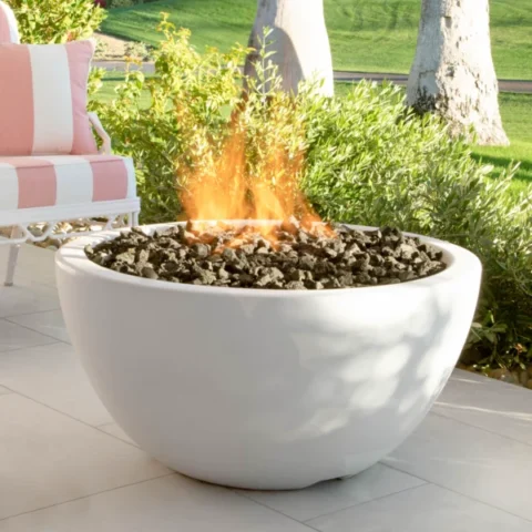 GFRC Concrete Luna Fire Bowl in White Limestone on the patio in a backyard.